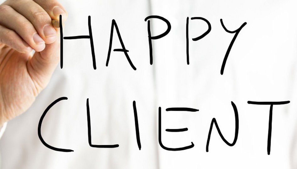 A person writes the words HAPPY CLIENT in large black letters on a transparent surface, with a white background behind them.