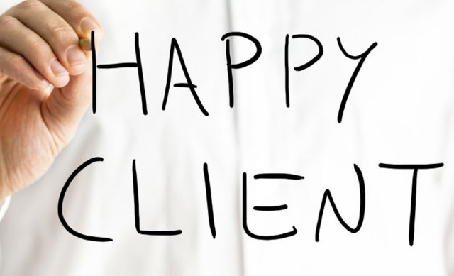 A person writes the words HAPPY CLIENT in large black letters on a transparent surface, with a white background behind them.